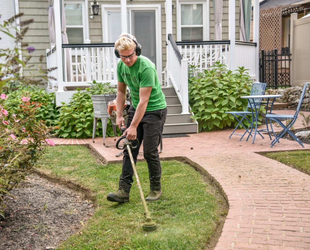 Man with a green t shirt cleaning his lawn—looking after a large garden.